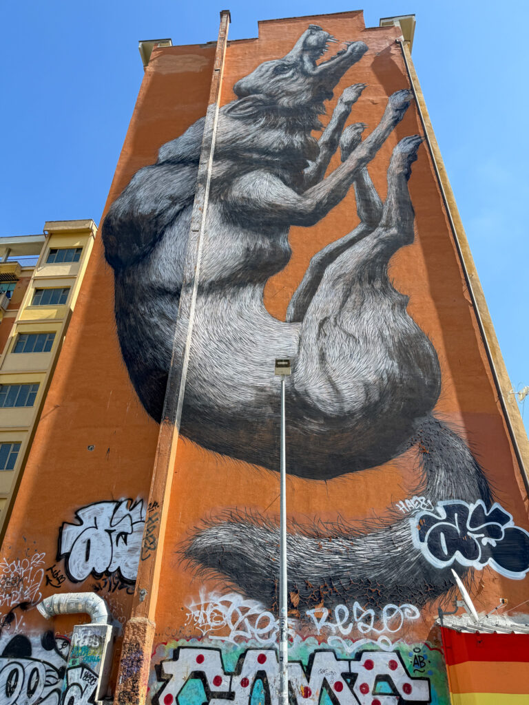 Graffiti art of a wolf on a tall orange wall on the side of a building